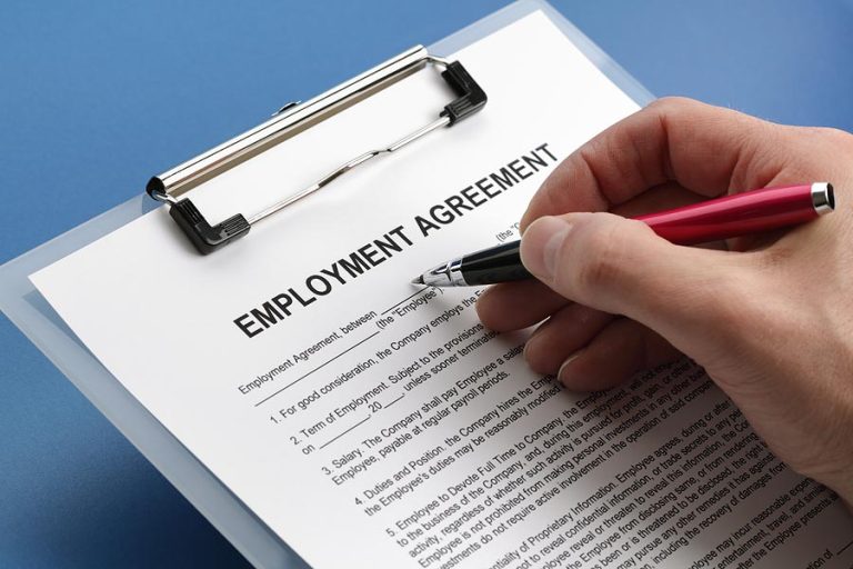 person signing paper on clipboard